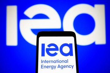 In this photo illustration, International Energy Agency (IEA) logo is seen on a smartphone and a pc screen. (Source: Getty Images)