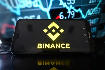 A Binance logo is seen displayed on a smartphone with stock market percentages on the background. Ilustrative photo. (Source: Getty Images)