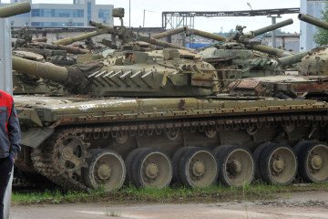 An employee looks at broken tanks parked during an open day at the Armored Vehicle repair plant in Strelna, outside Saint Petersburg, on August 5, 2016.