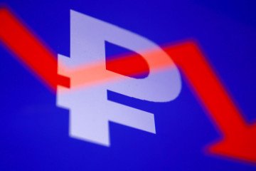 Russian ruble symbol displayed on a phone screen and an illustrative stock graph displayed on a screen are seen in this multiple exposure illustration photo taken in Krakow, Poland on February 28, 2022. (Source: Getty Images)