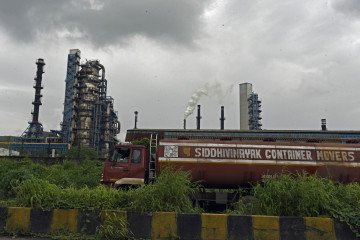 A tanker parks near an industrial facility as smoke rises from chimneys under overcast skies in Mumbai, India, on September 12, 2025. (Source: Getty Images)