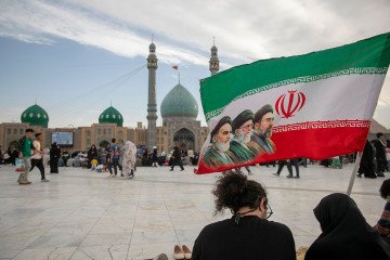 People hold a flag with Iran’s late and new supreme leaders during Eid al-Adha at the entrance of Jamkaran Mosque on May 26, 2026 in Qom, Iran. (Source: Getty Images)