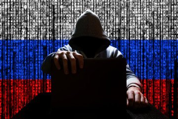 Illustrative photo of a person closing a laptop against a background of binary code in the colors of the Russian flag. (Source: Getty Images)