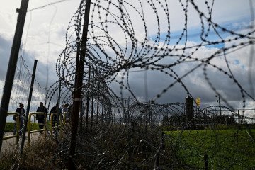 Tourists stand next to a razor-wire boundary fence along the Polish-Lithuanian border with the Russian exclave of Kaliningrad near the village of Grzybina, Podlaskie Voivodeship, near the Suwalki Gap on September 26, 2026. (Source: Getty Images) Tourists stand next to a razor-wire boundary fence along the Polish-Lithuanian border with the Russian exclave of Kaliningrad near the village of Grzybina, Podlaskie Voivodeship, near the Suwalki Gap on September 26, 2026. (Source: Getty Images)
