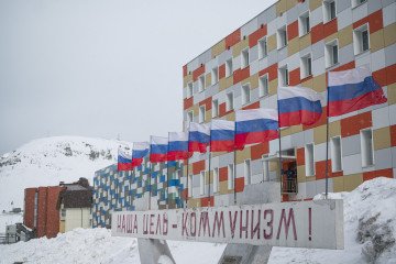 A Soviet-era slogan reading “Our goal is communism” stands in the snowstorm outside a Russian facility in Barentsburg, Svalbard — one of the last outposts of Moscow’s Arctic presence. (Source: Getty Images)