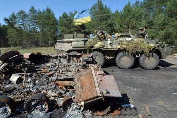 An armoured personnel carrier (APC) bearing the Ukrainian flag drives past a burned APC of Russian militants, outside Nickolayevka, a small eastern Ukrainian city near Sloviansk, on July 5, 2014. (Source: Getty Images)