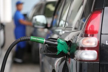 A fuel pump handle rests in the refilling nozzle of an automobile a gas station. Illustrative image. (Source: Getty Images)