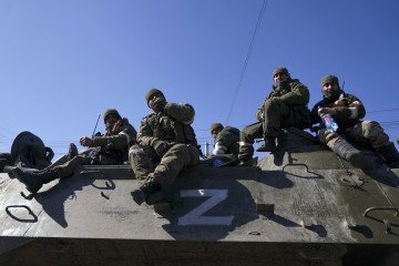Russian servicemen sit atop an armored vehicle marked with the “Z” symbol during the invasion of Ukraine in Mariupol, March 24, 2022. (Source: Getty Images)