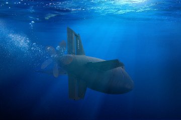Naval submarine on a mission travelling under deep blue sea water. (Source: Getty Images)