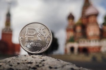 A Russian ruble coin is pictured in front of the Kremlin’s Spasskaya tower and St. Basil’s Cathedral in downtown Moscow on September 12, 2025. (Source: Getty Images)