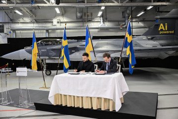 El primer ministro sueco, Ulf Kristersson, y el presidente ucraniano, Volodymyr Zelenskyy, firman una carta de intención frente a un avión de combate Gripen en Linköping, Suecia, el 22 de octubre de 2025. (Fuente: Getty Images)