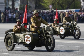 Russia Blocks Bank Accounts and Fabricates Charges to Force Foreign Nationals Into Military Participants wearing historical uniforms ride in WWII-era motorcycles adorned with stickers of the letter Z, which has become a symbol of support for Russian military action in Ukraine, during a military parade. Illustrative photo. (Source: Getty Images)