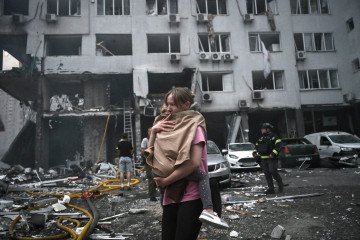 A woman holds her daughter outside a residential building damaged in a Russian ballistic missile strike on Kyiv, July 6, 2026. (Source: Getty Images)