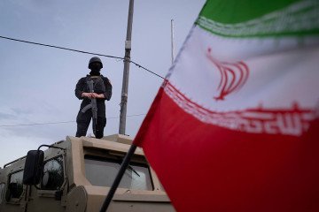 An armed Iranian police officer stands guard on an armored vehicle, monitoring the area during a state-run religious rally in downtown Tehran, Iran, on April 29. (Source: Getty Images)