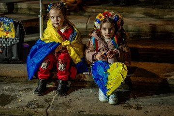 Two Ukrainian girls wearing traditional floral head-dresses stand wrapped in a Ukrainian flag during a rally in London marking the third anniversary of Russia’s full‑scale invasion. Illustrative photo. (Source: Getty Images)