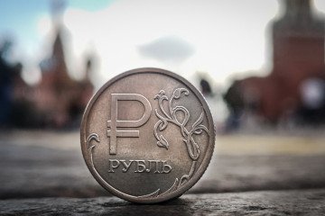 A Russian ruble coin is pictured in front of the Kremlin's Spasskaya tower and St. Basil's cathedral in downtown Moscow on September 12, 2025. Illustrative photo. (Source: Getty Images)