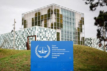 This photograph shows the “the International Criminal Court (ICC)” in the background with its logo on a sign in the foreground in The Hague, on February 23, 2026. (Source: Getty Images)