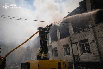 A firefighter sprays water onto the smoking roof of the Sumy kindergarten after the Russian drone strike. (Source: State Emergency Service of Ukraine)