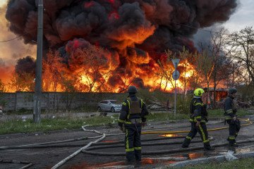 Rescue workers extinguish a fire at a recycling warehouse following a missile and drone strike. (Source: Getty Images)