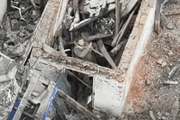 A Russian serviceman is seen amid debris and structural damage at a building in temporarily occupied territory. (Source: 158th Separate Mechanized Brigade)