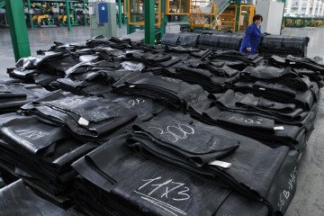 An employee passes strips of rubber, laid out at the ZAO Sibur Holding tire manufacturing plant in Voronezh, Russia, on November 18, 2011. Illustrative photo. (Source: Getty Image)
