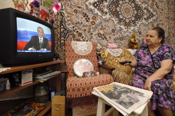 A woman watches Russian leader Vladimir Putin's address to the nation in a pre-recorded TV speech. (Source: Getty Images)