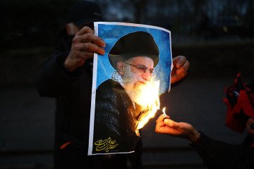Anti-Iranian regime protesters burn an image of Ayatollah Ali Khamenei, during a gathering outside the Iranian Embassy, central London, on January 12, 2026. (Source: Getty Images)