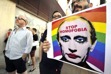 A demonstrator holds a poster depicting Russian leader Vladimir Putin with make-up as he protests in Madrid on August 23, 2013.