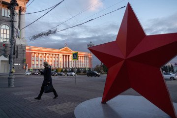 A woman walks past a red star installation, with the Kursk regional administration building. (Source: Getty Images)
