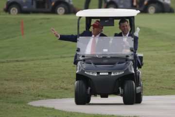US President Donald Trump and his son, Eric Trump, drive in a golf cart at his Trump National Doral Golf Club. (Source: Getty Images)