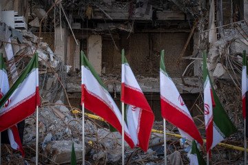 Iranian national flags are placed in front of the ruins of a building in Tehran, Iran. (Source: Getty Images)