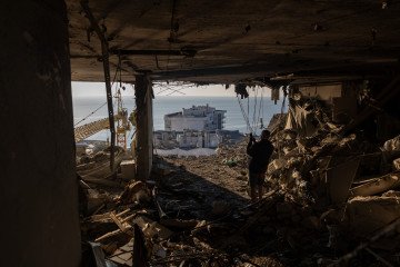 A man stands among the debris, looking out at the sea through a blown-out wall of an apartment destroyed by a Russian strike on September 17, 2026 in Odesa, Ukraine. (Source: Getty Images)