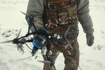 A soldier of Ukraine’s 13th Khartiia Brigade displays an FPV drone caught in a net during field tests of a net-launching counter-drone system, January 7, 2026. (Source: Getty Images)