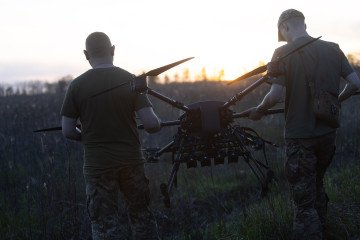 Ukrainian soldiers of the 127th Heavy Mechanized Brigade carry a Heavy Shot UAV across a field. (Source: Getty Images)