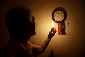 Blackouts and Water Crises Worsen in Occupied Crimea After New Wave of Ukrainian Drone Attacks A woman uses a candle to look at a clock during a power outage in the Crimean city of Simferopol. (Source: Getty Images)