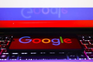 The Google logo is displayed on a mobile phone screen photographed with the Russian flag in the background, July 19, 2022. (Source: Getty Images)