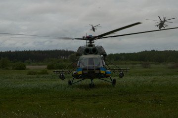 A Ukrainian Mi-8 helicopter stands as a pair of Mi-24s lift off on a combat mission, 2025. (Source: UNITED24 Media)
