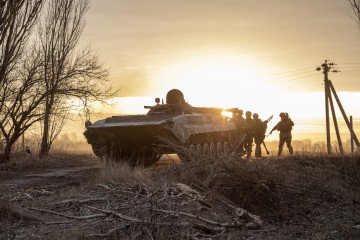 Ukrainian servicemen take cover behind a military armored vehicle during drills east of Kyiv, Ukraine, March 28th, 2022.