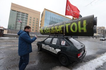 A man looks at the Lada VAZ 2109 car with Soviet flag and symbolic layout of the RS-28 "Sarmat" missile. (Source: Getty Images)