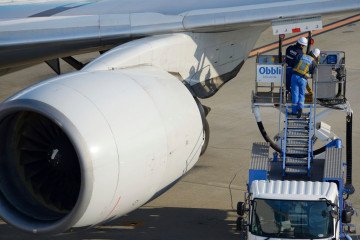 Employees stand on a fuel truck as they refuel an All Nippon Airways Co. (ANA) aircraft at Haneda Airport in Tokyo, Japan. (Source: Getty Images)