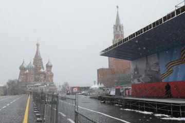 A Federal Protective Service officer stands on the podium prepared for the Victory Day military parade against the backdrop of the Kremlin’s Spasskaya Tower during a snowfall, on April 28, 2026, in Moscow, Russia. (Source: Getty Images)