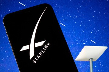 The SpaceX Starlink logo is seen displayed on a smartphone screen, with a Starlink satellite dish visible in the background. Illustrative Image. (Source: Getty Images) The SpaceX Starlink logo is seen displayed on a smartphone screen, with a Starlink satellite dish visible in the background. Illustrative Image. (Source: Getty Images)