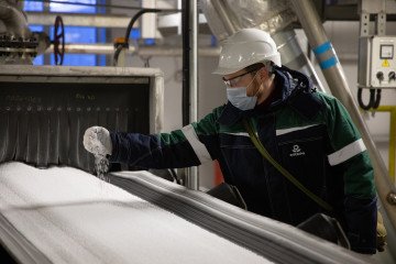 A worker inspects granules of phosphate fertilizer from a conveyor at the PhosAgro-Cherepovets fertilizer plant, operated by PhosAgro PJSC, in Cherepovets, Russia, on December 2, 2021. (Source: Getty Images)