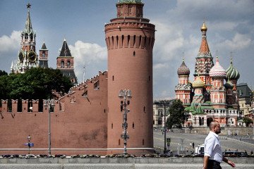 A pedestrian walks past the Kremlin and St. Basil’s Cathedral (R) in downtown Moscow on July 28, 2026. (Source: Getty Images)
