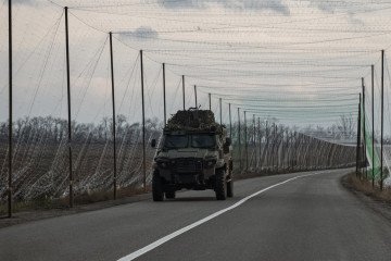 Vehículo blindado ucraniano circulando por carretera protegida con redes anti-drones cerca del frente en el este de Ucrania