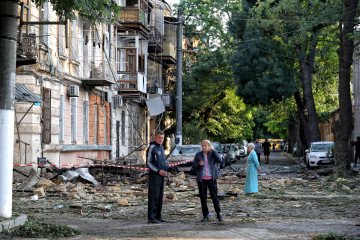 Russian Missile Strike on Odesa Region Kills 2, Injures 13, Damages Industrial Facility People stand in the street outside a building damaged by a Russian drone attack in Odesa, Ukraine, on June 10, 2025. (Source: Getty Images)