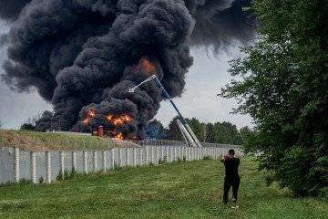 A fire burns at an oil depot in Voronezh, Russia, as a local resident records the scene following reports of a fuel tank blaze in the city, June 24, 2023.(Photo: Getty Images)