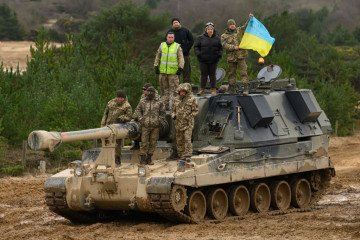 Ukrainian recruits and their British Armed Forces trainers pose for a photograph on an AS90 self-propelled artillery system at a military facility, on February 23, 2023 in Southern England. (Source: Getty Images)