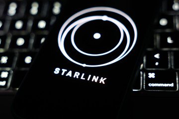 A laptop keyboard and Starlink logo displayed on a phone screen are seen in this illustration photo taken in Krakow, Poland on March 11, 2025. (Source: Getty Images)