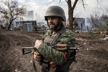 A Russian serviceman stands in front of destroyed buildings in Ukraine. (Photo: open source)